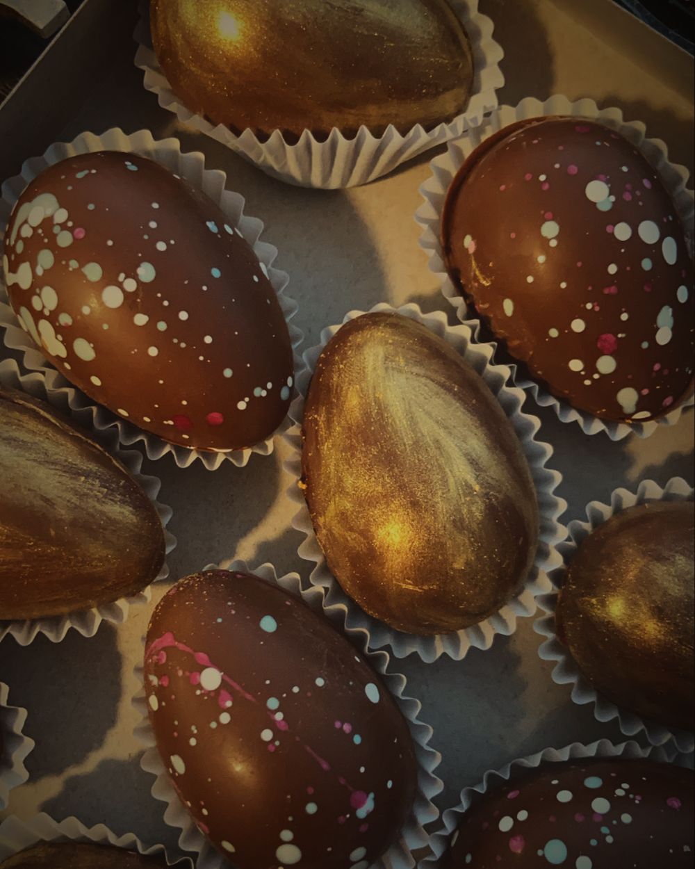 Chocolate Easter eggs, some brushed with gold and others speckled with colour